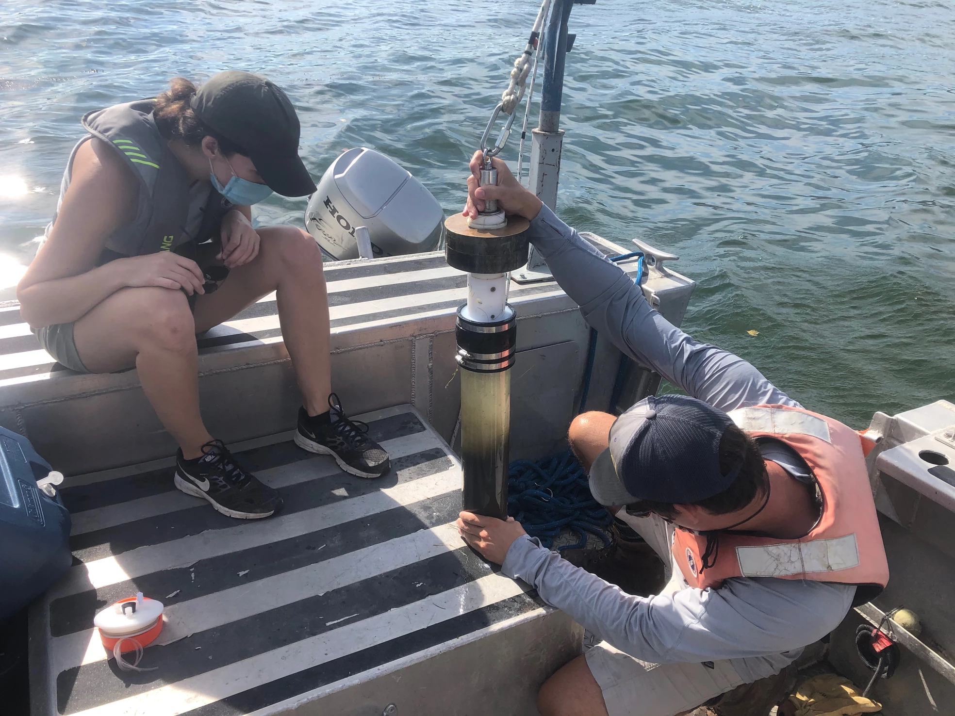 Scientists on a boat collecting sediments cores